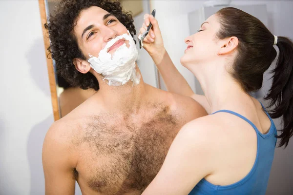 Mujer ayudando al hombre a afeitarse — Foto de Stock