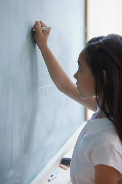 Girl writing on blackboard — Stock Photo, Image