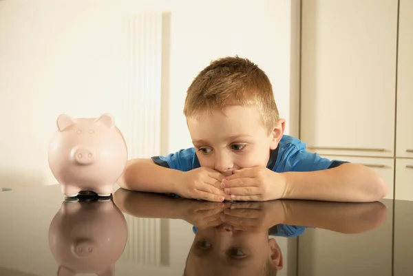 Menino acumulando dinheiro perto de porquinho banco — Fotografia de Stock