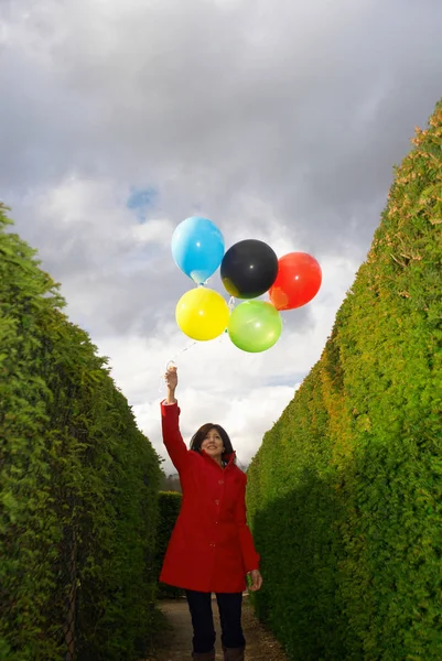 Vrouw in rode jas houden ballonnen — Stockfoto