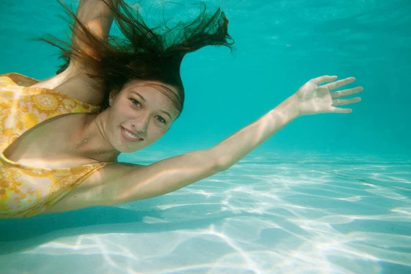 Ragazza nuotare sott'acqua sorridente alla macchina fotografica — Foto Stock