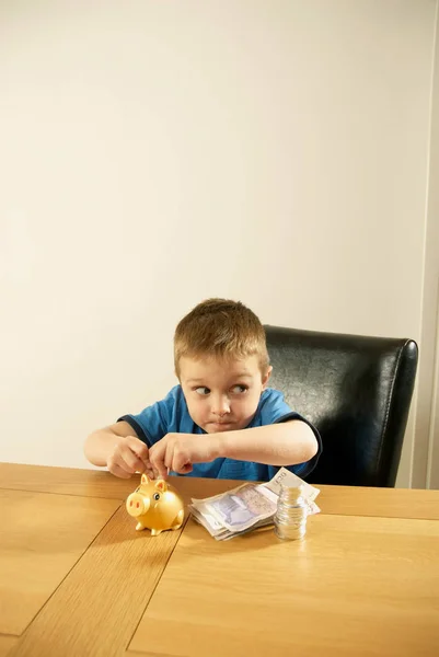 Pojken att lägga pengar i spargrisen — Stockfoto