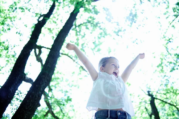 Menina com braços levantados andando na floresta — Fotografia de Stock