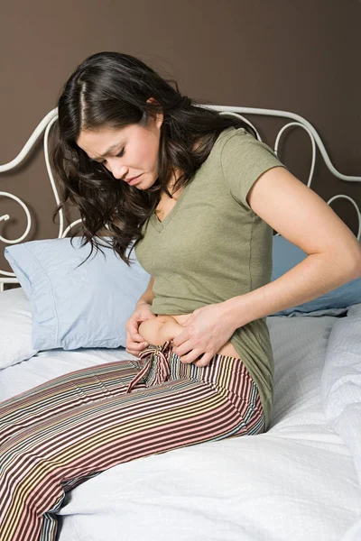 Mujer joven mirando el estómago — Foto de Stock