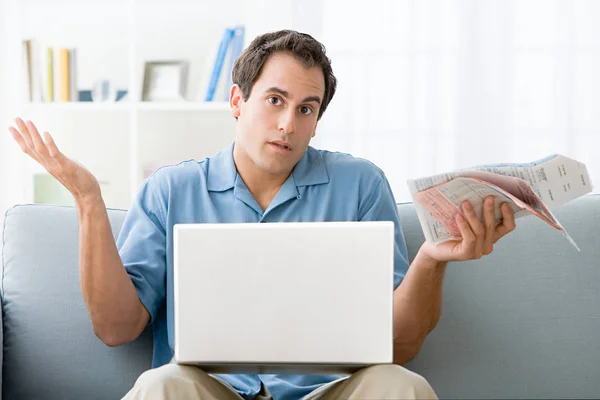 Uomo seduto con bollette e laptop — Foto Stock