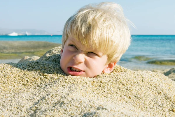 Boos jongen begraven in zand — Stockfoto