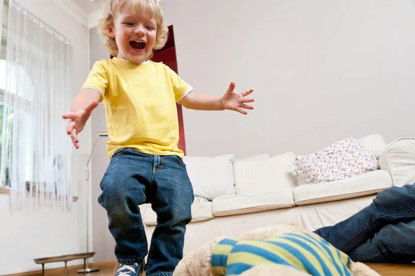 Niño jugando y saltando en la sala de estar — Foto de Stock