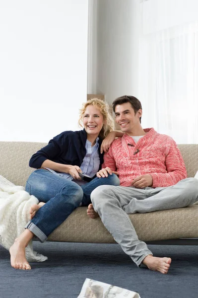 Pareja viendo televisión sentada en el sofá — Foto de Stock