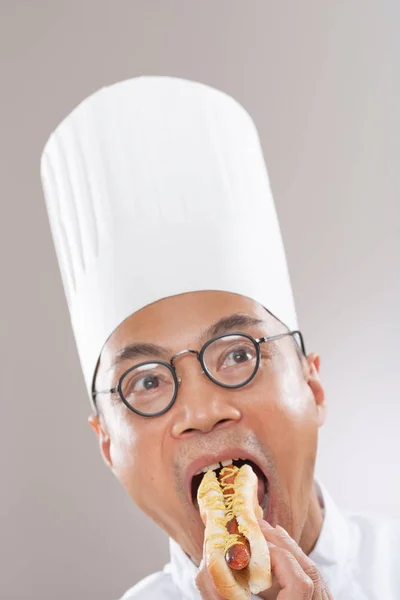 Chef en gorra comiendo hot dog —  Fotos de Stock