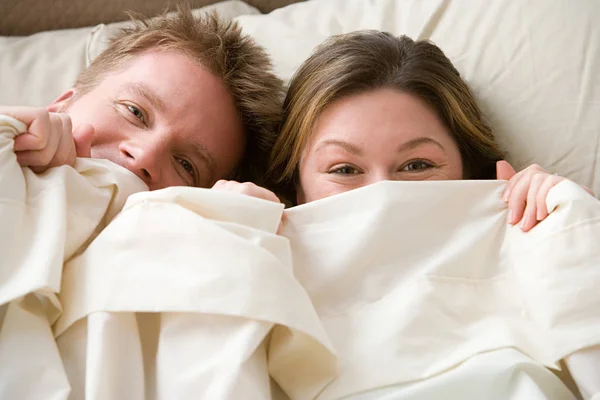 Couple hiding under sheet — Stock Photo, Image
