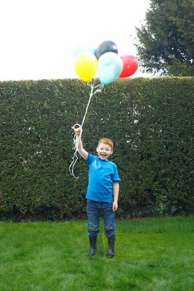 Boy holding bunch of balloons — Stock Photo, Image