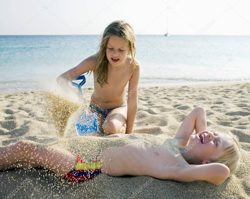 girl pouring sand on boy
