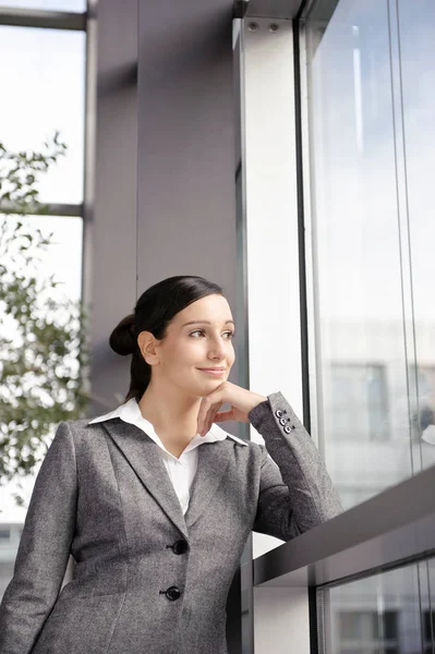 Affärskvinna ser från office-fönstret — Stockfoto