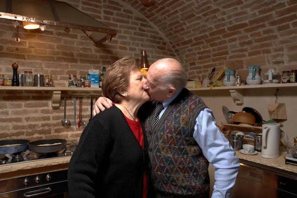 Поцелуи старшей пары на кухне — стоковое фото