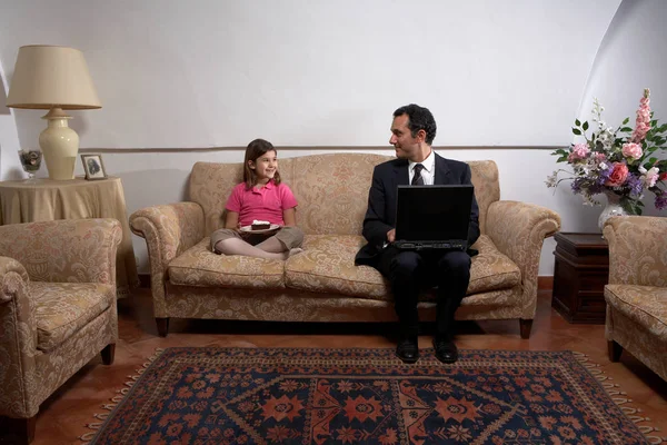 Чоловік використовує ноутбук і дивиться на дочку — стокове фото