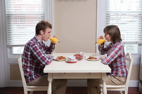 Casal beber suco na mesa da cozinha — Fotografia de Stock