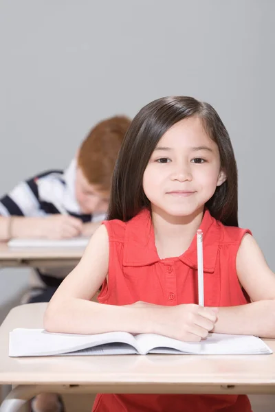 Flicka i klassrummet sitter vid skrivbord — Stockfoto