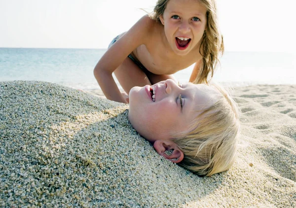 Mädchen mit Junge im Sand begraben — Stockfoto