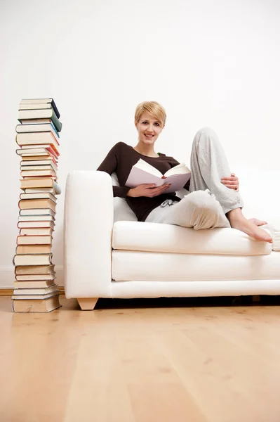 Mulher lendo um livro sentado em Sof — Fotografia de Stock