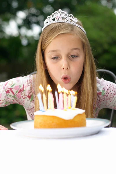 Menina em chapéu de festa soprando velas — Fotografia de Stock