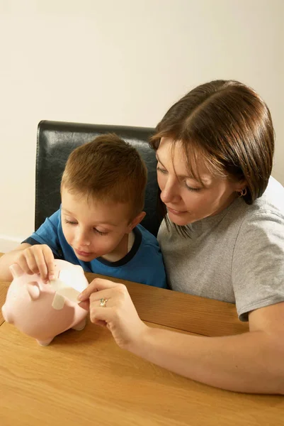 Mãe e filho reparar porquinho banco — Fotografia de Stock