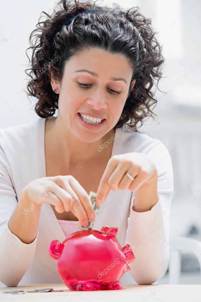 woman putting money in piggy bank