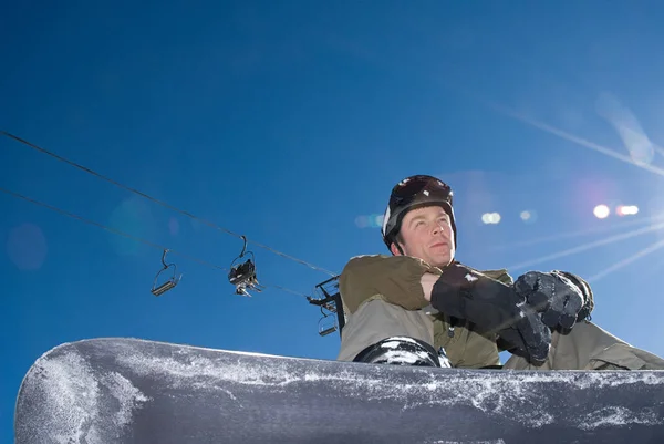 Snowboarder sentado bajo telesilla — Foto de Stock