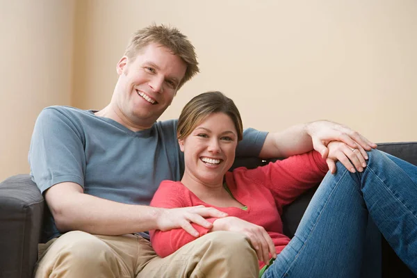 Pareja sentada en el sofá y mirando a la cámara — Foto de Stock