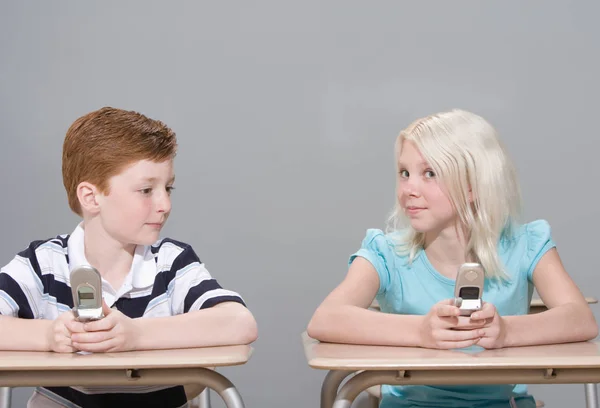 Niño y niña con teléfonos móviles — Foto de Stock