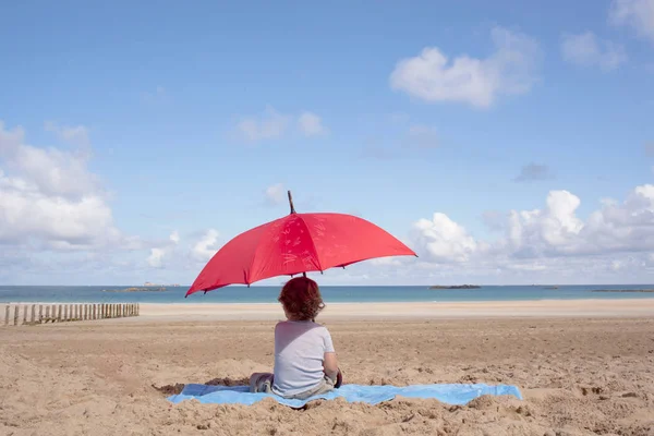 Pojken sitter under parasoll — Stockfoto