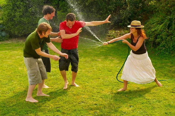女性が男性を庭のホースで噴霧 — ストック写真
