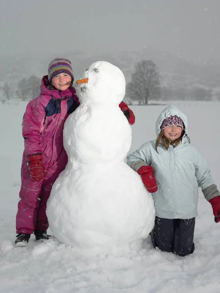 Niñas Con Snowman Mirando Cámara —  Fotos de Stock