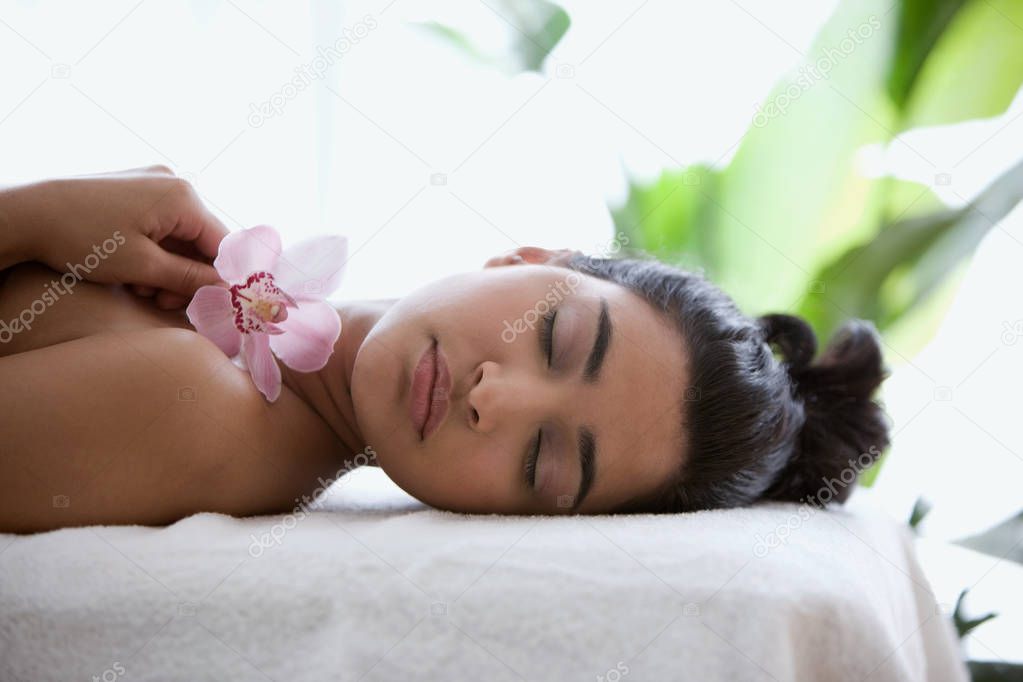 Young woman on massage table with orchid flowers