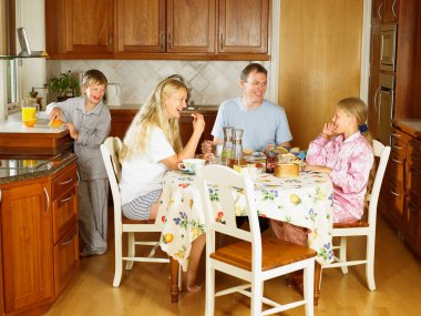 Family sitting at kitchen table eating clipart