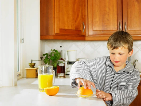 Mladý Chlapec Dělat Pomerančový Džus Kuchyni — Stock fotografie