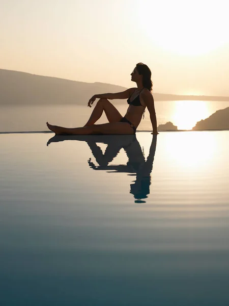 Woman sitting on the edge of a pool