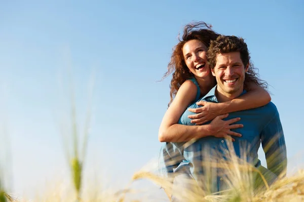 Man carrying woman in a wheat field