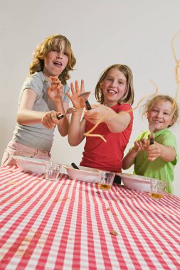 Children flicking spaghetti at home clipart