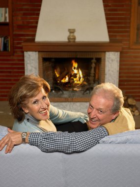 Senior couple relaxing in living room clipart