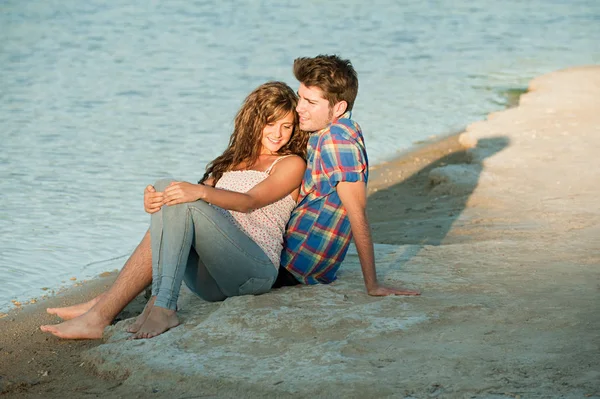 一对年轻夫妇坐在湖边 — 图库照片