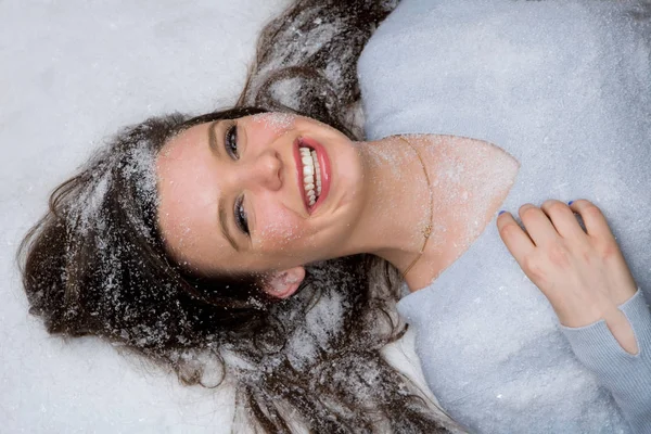 Mujer sonriendo y tendida en la nieve — Foto de Stock