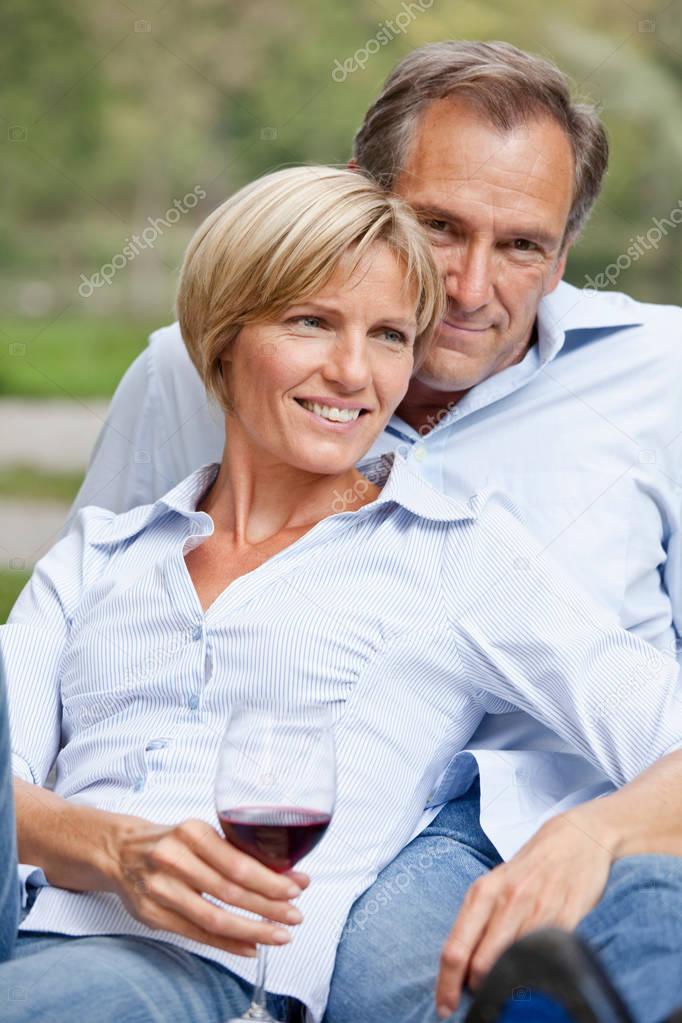 Middle aged couple sitting close outdoors