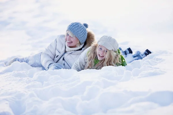 Moeder en dochter liggen in de sneeuw — Stockfoto