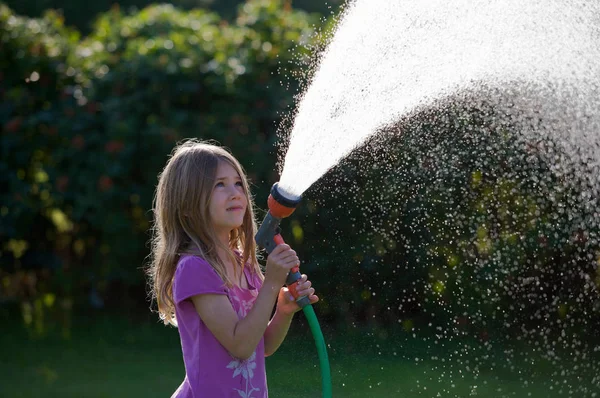 ホースで水を噴霧若い女の子 — ストック写真