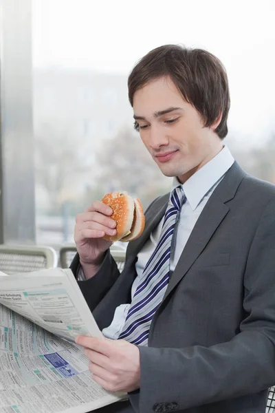 Halbe Ansicht Des Geschäftsmannes Der Zeitung Liest Und Sandwich Isst — Stockfoto