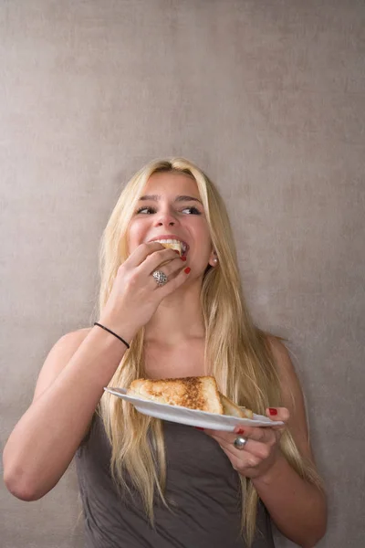 Mulher comendo sanduíche e sorrindo — Fotografia de Stock