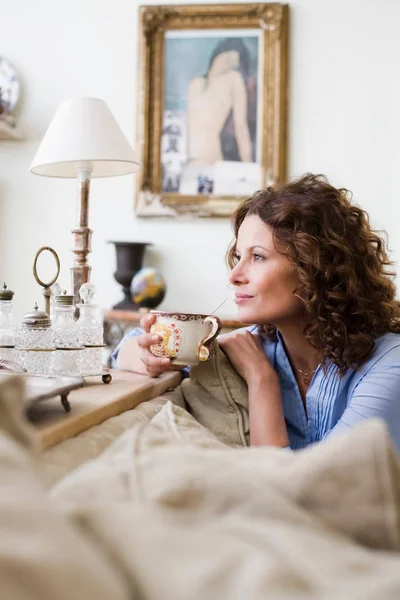 ソファの上のコーヒー カップを保持している女性 — ストック写真