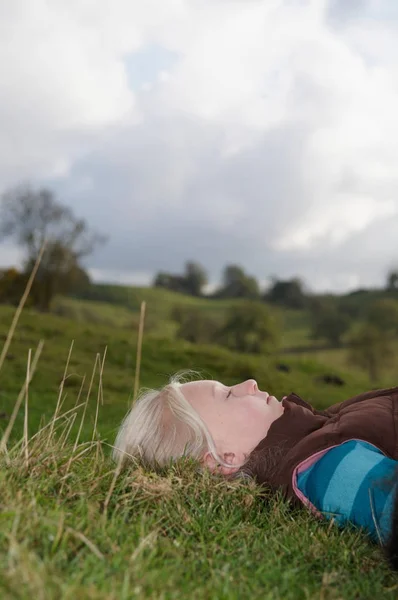 空を見て草の上に横たわっている女の子 — ストック写真