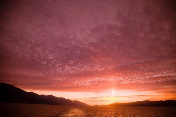 背景下多云粉红色天空日落期间的水面 — 图库照片