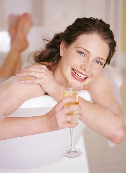 Жінка лежить у ванні з келихом шампанського — стокове фото